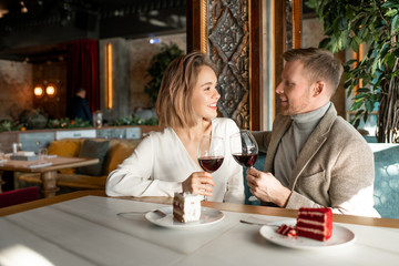 Young romantic couple with glasses of red wine talking and making toast