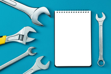 Wrenches, notebook copy space on blue background top view.