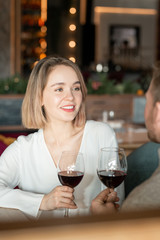 Pretty young woman with toothy smile talking to her boyfriend while making toast