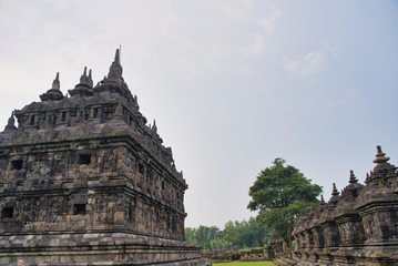 Old stone building of a Hindu temple surrounded by grass and stone columns