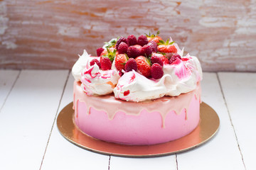 Pink cake with meringue, melted chocolate and fresh raspberries and strawberries.