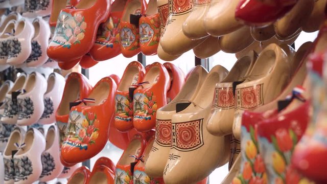 Panning medium shot of typical colourful dutch clogs, hanging on the wall, in a store.