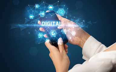 Female hand holding smartphone with DIGITAL inscription, modern technology concept