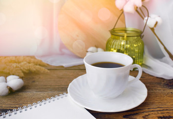 Still life kitchen details. Coffee cup, notepad, dried flowers and light glass on wooden desk. Fall  concept. Cozy home. Sunlight effect.