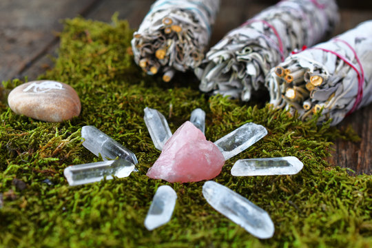 A close up image of a rose quartz crystal grid and smudge sticks with reiki healing symbol. 