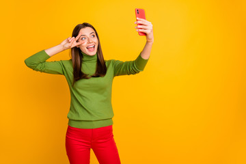 Positive cheerful funky girl have winter rest relax abroad make selfie on her smartphone show v-sign wear stylish trendy outfit isolated over yellow color backround
