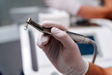 Dentist hand with a drill in white gloves. Dental drill in dental office. Closeup, selective focus.