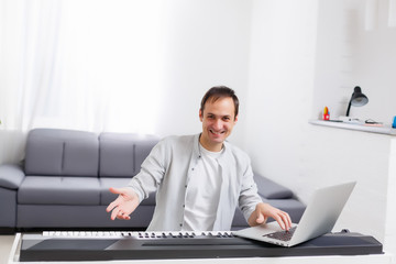 A man learning to play piano online with a computer staying at home. Concepts of self taught, staying at home and working online