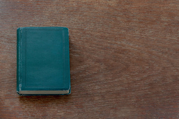An old shabby book lies on an old shabby wooden table. Close-up. Warm colors.