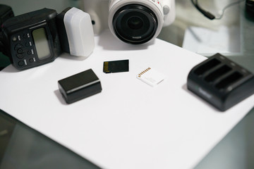 camera ,flash,charger,battery and memory cards on table with white paper with copy space