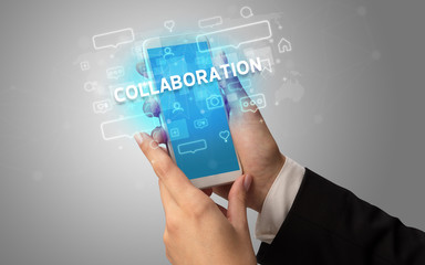 Female hand typing on smartphone with COLLABORATION inscription, social media concept