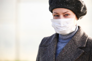 Young woman in the protective mask over the blurred background.