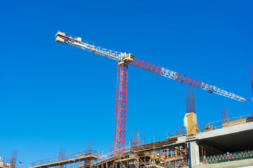 Fototapeta na wymiar Single high-rise construction crane on the blue sky background. Building construction site with crane. 