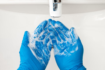 Hands with blue gloves washing with soap