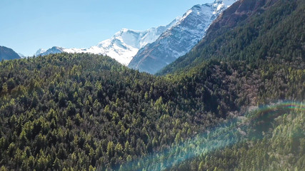 View on Himalayas along Annapurna Circuit Trek, Nepal. There is a dense forest in front, covering vast region. High, snow caped mountain chains in the back. Serenity and calmness.