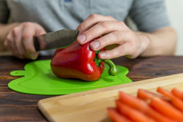 a man is slicing tomatoes and red onions on a green Board. vegetable vitamin salad