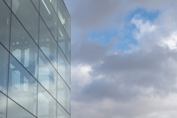 Fototapeta na wymiar Glass wall of modern office building against cloudy sky. Copy space for text.