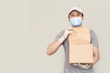 Fototapeta na wymiar The courier is holding a cardboard box of medical rubber gloves and a mask. a copy of the space. Fast delivery by courier. Online stores and Express delivery . social distancing