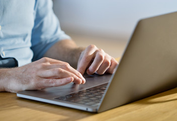 Successful businessman working behind a laptop at home. Blogger man maintains his personal blog on a laptop. Close-up