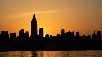 New York City Skyline in silhouette against a golden sunrise