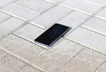 The lost smartphone is lying on the sidewalk.