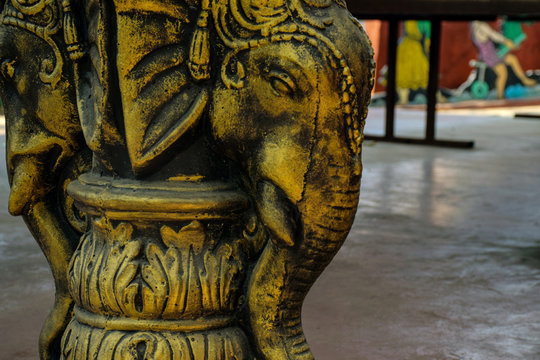 Picture of ancient carving of an elephant on a pillar and painted with golden color