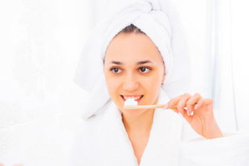 Beautiful woman with a toothbrush smiling. A young woman is brushing her teeth in the bathroom. Dental hygiene.