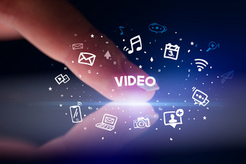 Finger touching tablet with drawn social media icons and VIDEO inscription, social networking concept