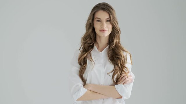 A pleased smiling young woman is shaking her finger negatively isolated over a gray background in studio