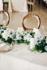 Wedding table decorated with tablecloth, fresh flowers composition, candles, plates and glasses