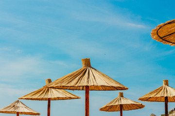 Obraz na płótnie Canvas Thatched beach umbrellas against sky. Summer photo