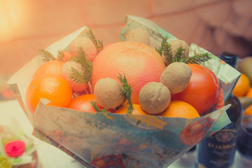 Bouquet of citrus fruits with spruce branches. Winter new year bouquet with walnuts, grapefruit, tangerines, persimmons. Orange holiday table decoration and birthday gift. 
