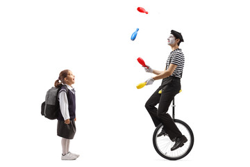 Schoolgirl watching a clown juggling and riding a unicycle