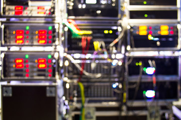 Blurred background of backstage area and tech zone with rack amplifiers, signal splitters, flight cases and radio microphone systems. Professional sound equipment for a concert with bokeh effect.