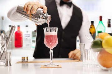 Bartender pouring a cocktail in a glass