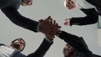Close up of happy multiethnic adult business people holding hands together. Team spirit in a modern multinational office.