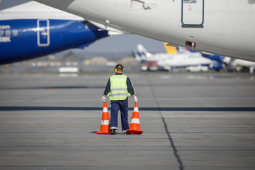 Man for an airport staff on the runway between commercial airplanes.