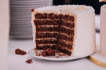 A cut of a wedding cake with chocolate cakes and cream, next to it there are sponge cake crumbs