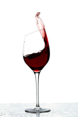 Close up view of splashing red wine in glass isolated on white background. 