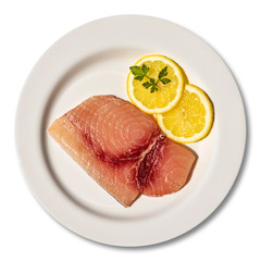 Macro close-up of a plate with a slice of raw, fresh swordfish. Dish garnished with two round slices of lemon and parsley leaf. Isolated on white background. Ready for cooking