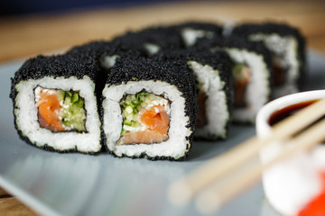 Sushi rolls with salmon, rice, nori, cremette cheese and on a white creamic plate.