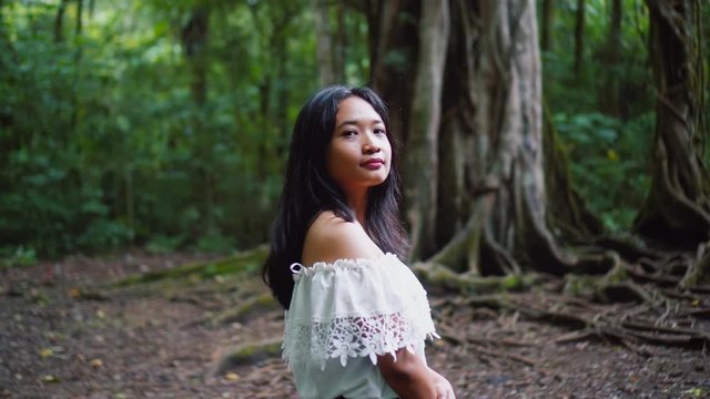Beautiful asian girl in amazing jungle forest turn and look into camera.