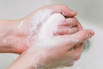 Fototapeta premium Woman uses soap and washes her hands under a faucet. Hygiene and hand cleaning. Prevention and control of coronavirus.