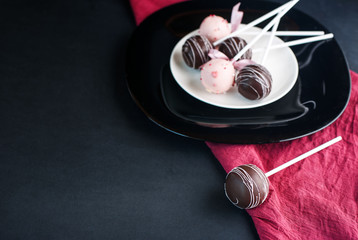 Delicious cake pops on a plate in a dark way.