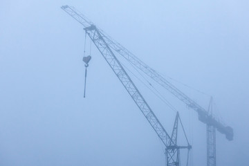 view of construction cranes in the fog