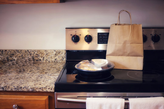 A Plastic Container Of Takeout Food On A Kitchen Stove