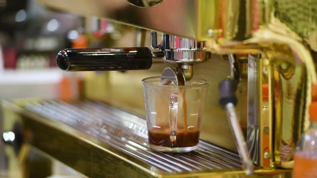 Barista making coffee with coffee machine in cafe. The Barista maker is put cup to machine for wait coffee liquid in coffeeshop. when start of work or workout is relax time for drink hot cup. 