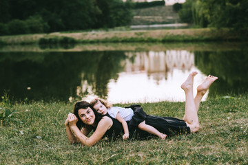 Handsome young father and beautiful mother in sunny summer nature playing with their cute small childrens