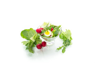 spring salad with arugula, boiled eggs, fresh radish, salad leaves in a glass bowl