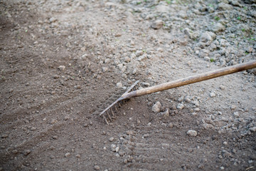 Garden work in the spring. Rake on the ground in a spring garden